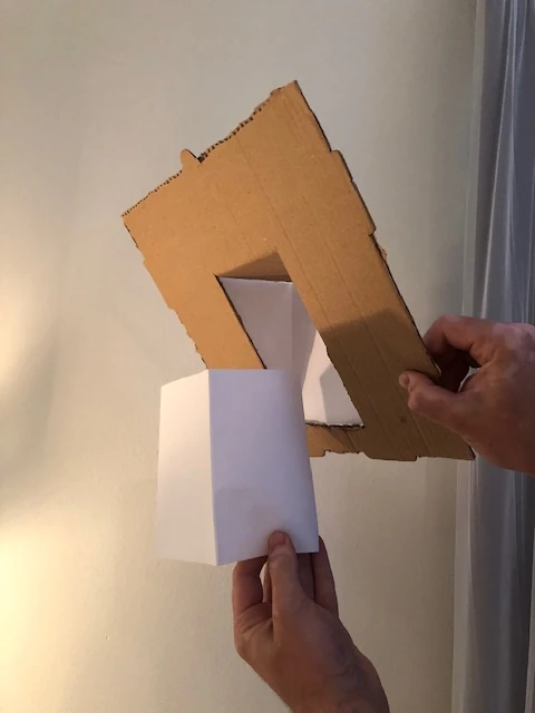 Cardboard and folded-paper study testing the altered fixture plane